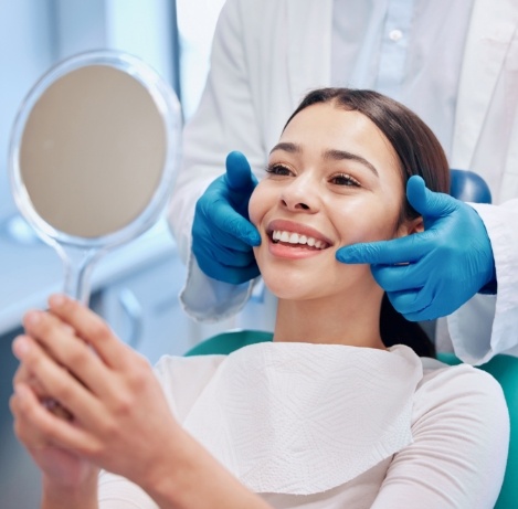 Young woman in dental chair admiring her new smile in a mirror