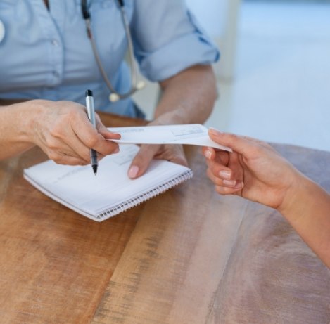 Patient handing a paper check to a dental team member