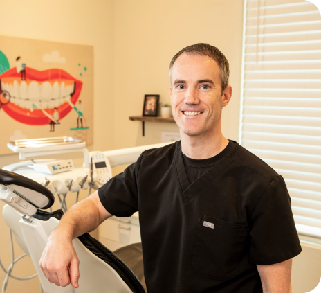 Doctor Matt Cole smiling while resting arm on dental chair